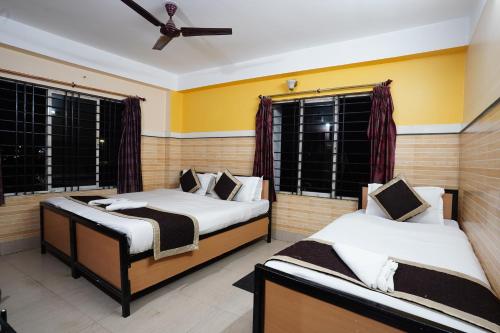two beds in a room with two windows at Tirupati Lodge NJP in Siliguri