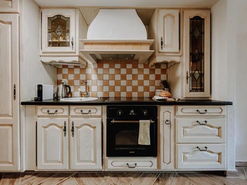 a kitchen with white cabinets and a black oven at Cosy and modern apartment closed to the ski lift in Crans-Montana