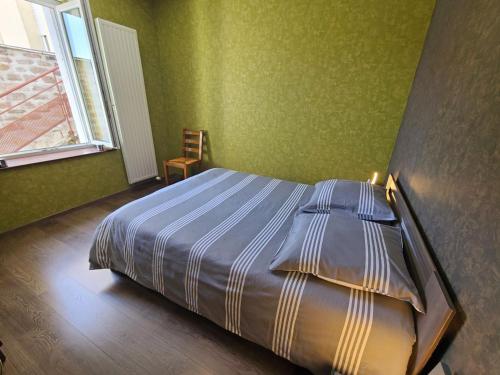 a bedroom with a bed with green walls and a window at Charmant T2 rénové avec cour privée - centre d'Épinal, proche gare et commodités - FR-1-589-265 in Épinal