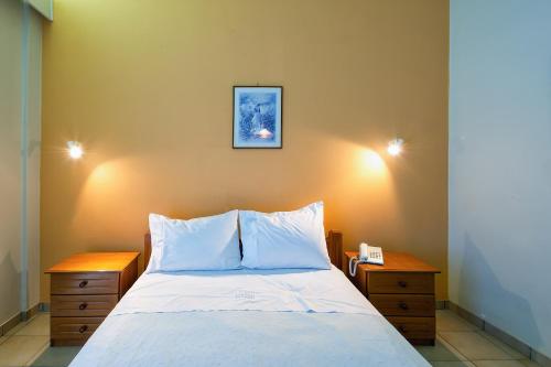 a bedroom with a white bed with two night stands at Hotel Fotini in Kalamata