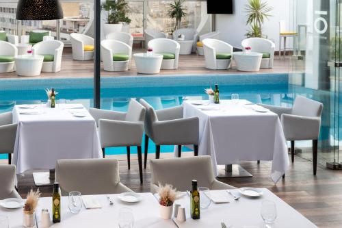 a restaurant with white tables and chairs and a pool at Mövenpick Hotel Casablanca in Casablanca
