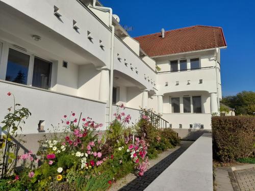 a white house with flowers in front of it at Demizson Panzió in Kehidakustány