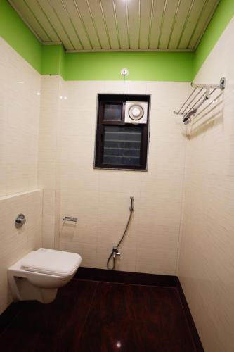 a bathroom with a toilet and a window at Tirupati Lodge NJP in Siliguri