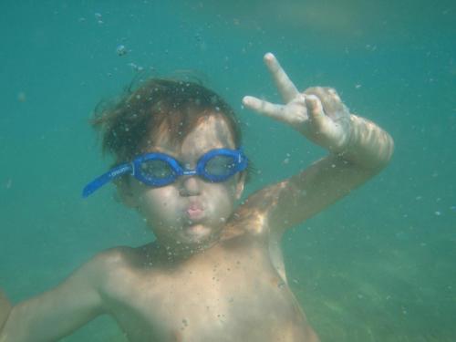 a young boy with blue glasses swimming in the water at Lulak Studio Apartments in Orebić