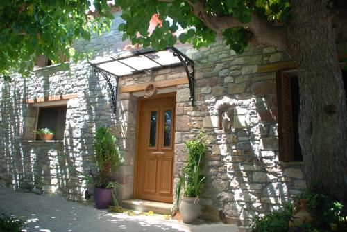 a stone house with a wooden door and potted plants at ''The Stone'' in Agios Vlasios