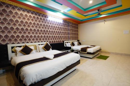 a room with two beds and a colorful ceiling at Tirupati Lodge NJP in Siliguri