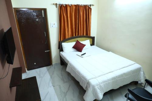 a bedroom with a white bed with a red pillow at Babu Naidu Residency in Vellore