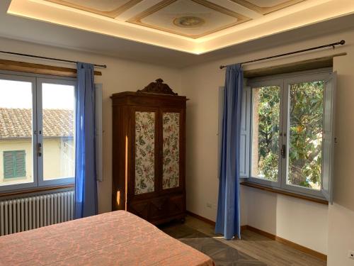 1 dormitorio con 1 cama y 2 ventanas con cortinas azules en Villa Paglicci Reattelli Agriturismo en Castiglion Fiorentino