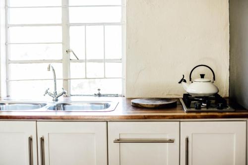 a kitchen with a sink and a tea kettle on a stove at Bokrivier Cottages in Greyton