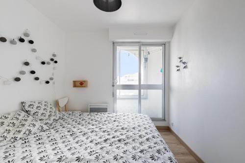a white bedroom with a bed and a window at À 50m de la Grande Plage, appartement pour 4 in Saint-Gilles-Croix-de-Vie