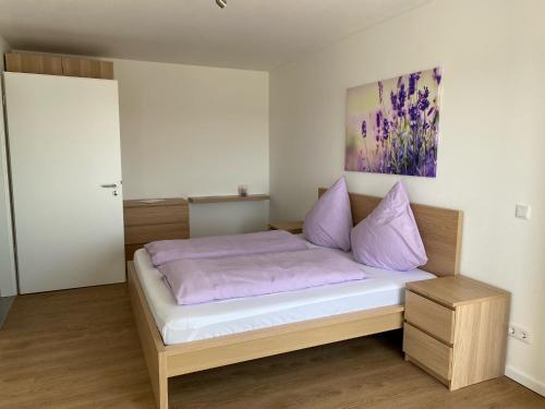 a bedroom with a bed with purple pillows and a painting at Ostwall Terrassen Apartment 5.33 in Bocholt