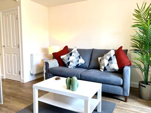 sala de estar con sofá azul y mesa blanca en New Stylish Cambridge Townhouse (Free parking), en Long Stanton