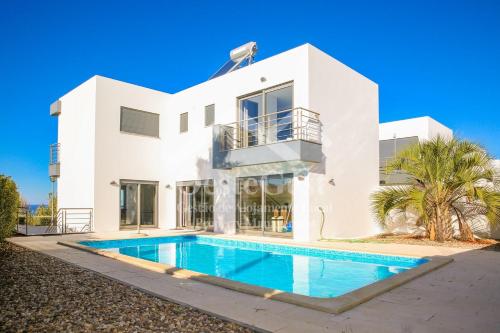 a white house with a swimming pool in front of it at Villa Azinhança do Mar in Lourinhã