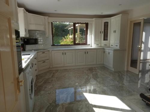 a large kitchen with white cabinets and a window at Impeccable 5-Bed Cottage in fahan buncrana in Buncrana