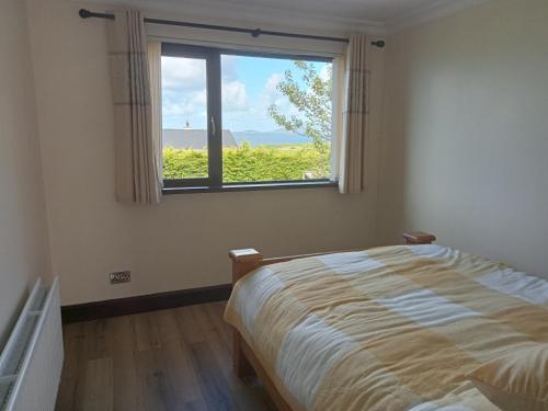 1 dormitorio con cama y ventana en Impeccable 5-Bed Cottage in fahan buncrana, en Buncrana