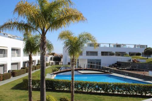 a swimming pool with palm trees in front of a building at Charming Tavira - Pools Pet-Friendly Golf in Tavira