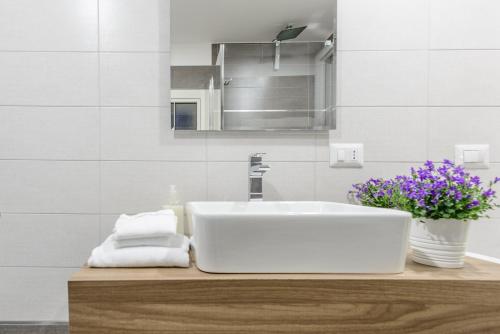 un bagno con lavandino bianco e vaso di fiori di Le Mummarelle Apartments a Napoli