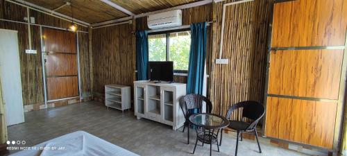 a room with a table and chairs and a television at Mango Valley Resort Ganpatipule in Ratnagiri