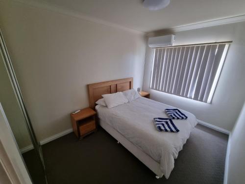 a small bedroom with a bed and a window at Seafront Unit 60 in Jurien Bay