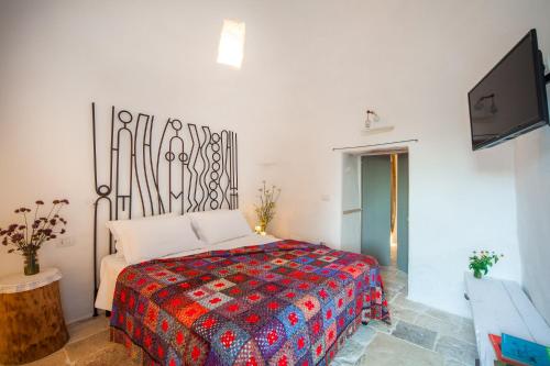 a bedroom with a bed and a flat screen tv at Trulli 18cinquantanove in Cisternino