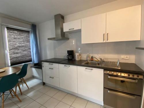 a kitchen with white cabinets and a sink and a table at Montpellier : Appartement Cosy et très fonctionnel in Montpellier