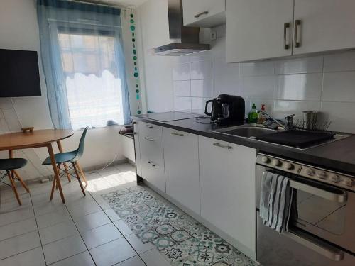 une cuisine avec des armoires blanches, une table et un évier dans l'établissement Montpellier : Appartement Cosy et très fonctionnel, à Montpellier
