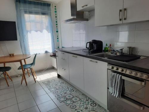 a kitchen with white cabinets and a table and a sink at Montpellier : Appartement Cosy et très fonctionnel in Montpellier