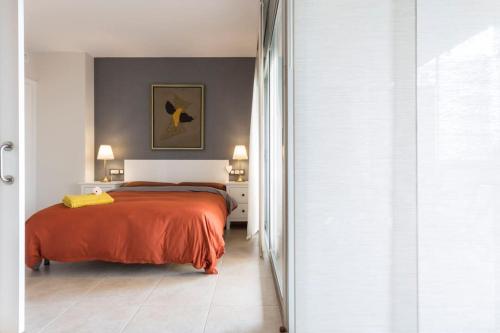 1 dormitorio con 1 cama con colcha de color naranja en Piso de 2 habitaciones, 3 piscinas y cerca del mar, en Roses