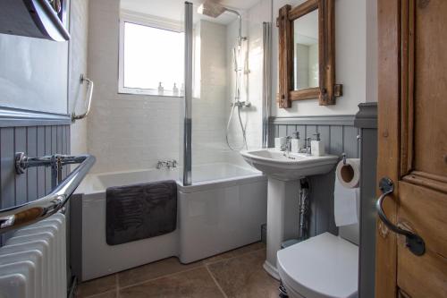 a bathroom with a sink and a tub and a toilet at Stylish Town Centre House with Garden and Parking Opposite in Bury Saint Edmunds