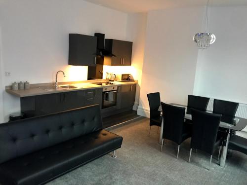 a living room with a couch and a table and a kitchen at 77 Park Road Apartments in Blackpool