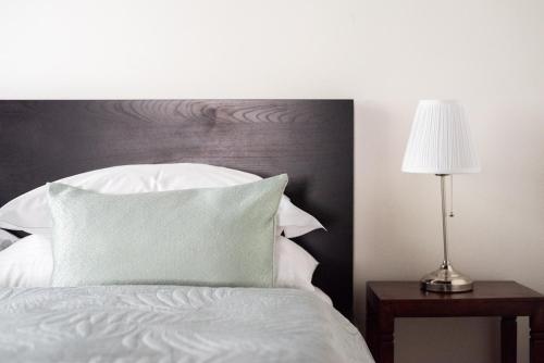 a white bed with a wooden headboard and a lamp at St. George Apartments in Prague
