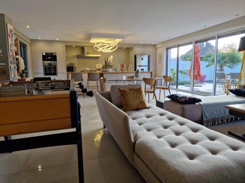 a living room with a couch and a table at MAGNIFIQUE VILLA LUXE COSY POPPIES HOLIDAY - Normandie Beach Racing, Flipper, Baby-foot, SPA, Jardin Méditerranéen, Plage Riva Bella à 300m, Mer à Pied, Tout Confort, Idéale Familles & Groupes, EVJ à Ouistreham, Proche Cabourg, Week-end & Courts Séjours ! in Ouistreham