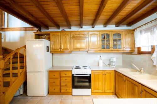 a kitchen with a white refrigerator and wooden cabinets at Chrysanthe [ Portaria ] Traditional Pelion House in Portariá