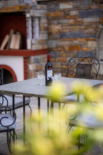 a bottle of wine sitting on a table with glasses at Chrysanthe [ Portaria ] Traditional Pelion House in Portariá
