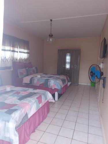 a bedroom with two beds and a tiled floor at FARANAS in Pietermaritzburg