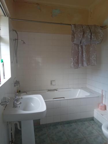 a white bathroom with a tub and a sink at FARANAS in Pietermaritzburg