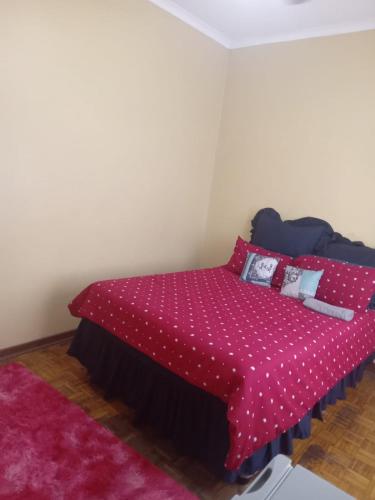a bedroom with a bed with a red comforter at FARANAS in Pietermaritzburg
