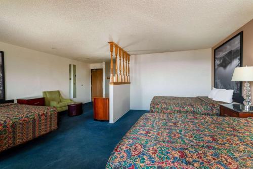 a hotel room with two beds and a chair at Super 8 by Wyndham Pendleton in Pendleton