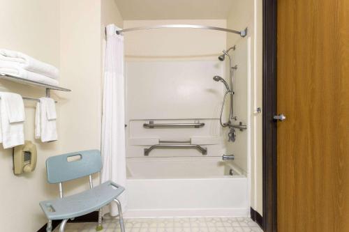 a bathroom with a bath tub and a blue chair at Super 8 by Wyndham Pendleton in Pendleton