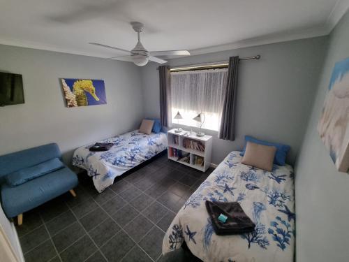 1 dormitorio con 2 camas, silla y ventana en Ocean Beach Chalet 18, en Jurien Bay