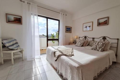 een witte slaapkamer met een groot bed en een raam bij Sunny Apart W Balcony in Algarve by LovelyStay in Ferragudo