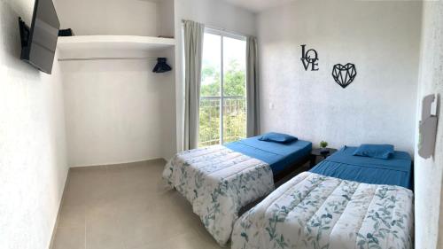 two beds in a room with a window at Departamento 2 habitaciones vista a la alberca Nube by EITA in Cancún