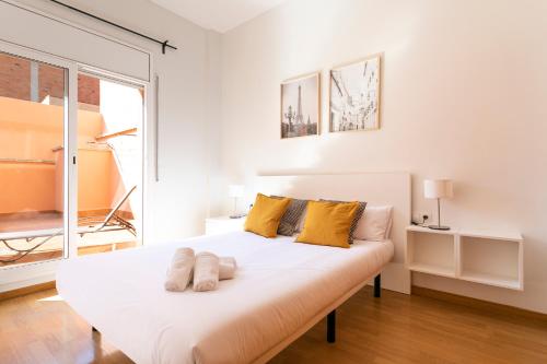 1 dormitorio con 1 cama blanca grande con almohadas amarillas en AB North Barcelona Apartments, en Barcelona