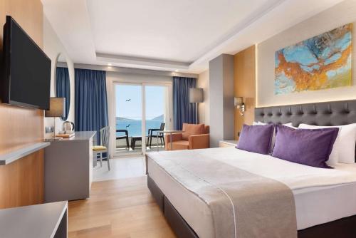 een hotelkamer met een groot bed met paarse kussens bij La Quinta by Wyndham Bodrum in Bodrum City