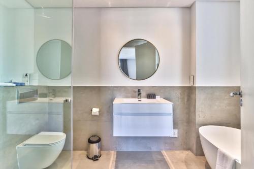 a bathroom with a toilet and a sink and mirrors at Luxury three Bedroom Apartment - fully furnished and equipped in Cape Town