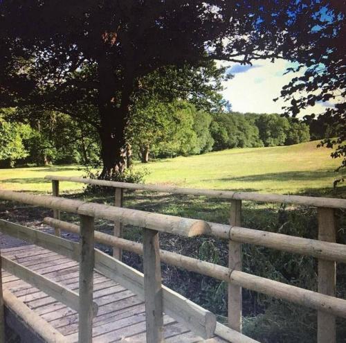 a wooden fence with a tree and a field at Kingfisher in Chirk