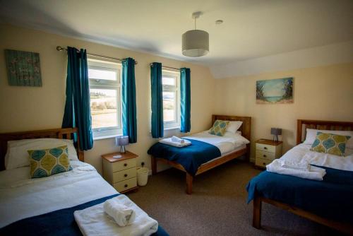 a bedroom with two beds and blue curtains at Lower Pentre in Llanddewi Ystradenny