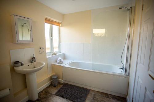 bagno con vasca bianca e lavandino di Lower Pentre a Llanddewi Ystradenny