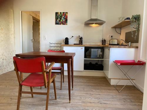 a kitchen with a wooden table and red chairs at Cosy appartement dans le Perche in Val-au-Perche