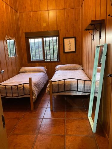 two beds in a room with wooden walls at Cigarra Sierra in Córdoba